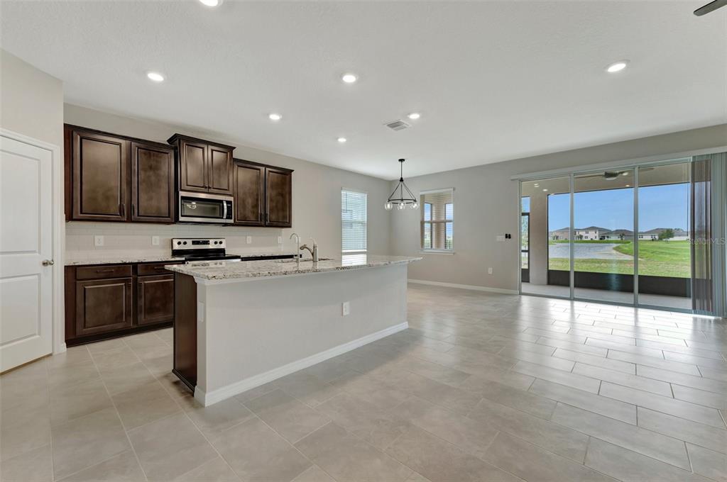 5210 Grove Mill Loop Lakewood Ranch, FL 34211 - Photo 4 of 48 a large kitchen with stainless steel appliances a large counter top a stove a microwave a sink and a refrigerator