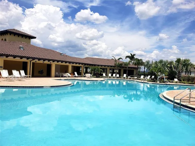 a view of swimming pool with lawn chairs and plants