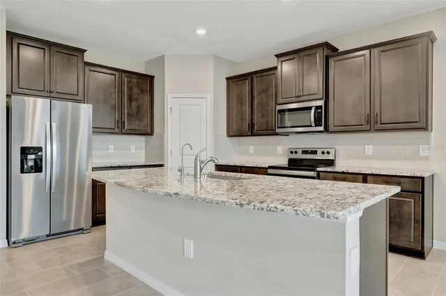 a kitchen with stainless steel appliances granite countertop a refrigerator a stove a sink and a microwave