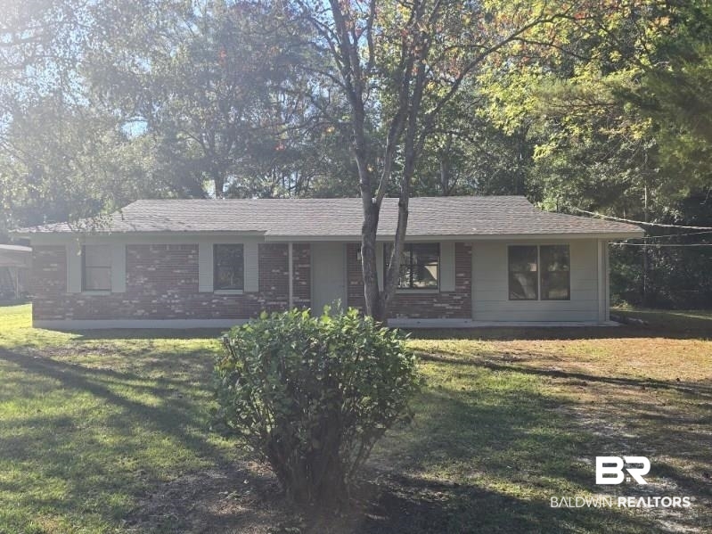 1404 Dailey Street Brewton, AL 36426 - Photo 1 of 25 Ranch-style house with a front yard, brick siding, view of wooded area, and roof with shingles