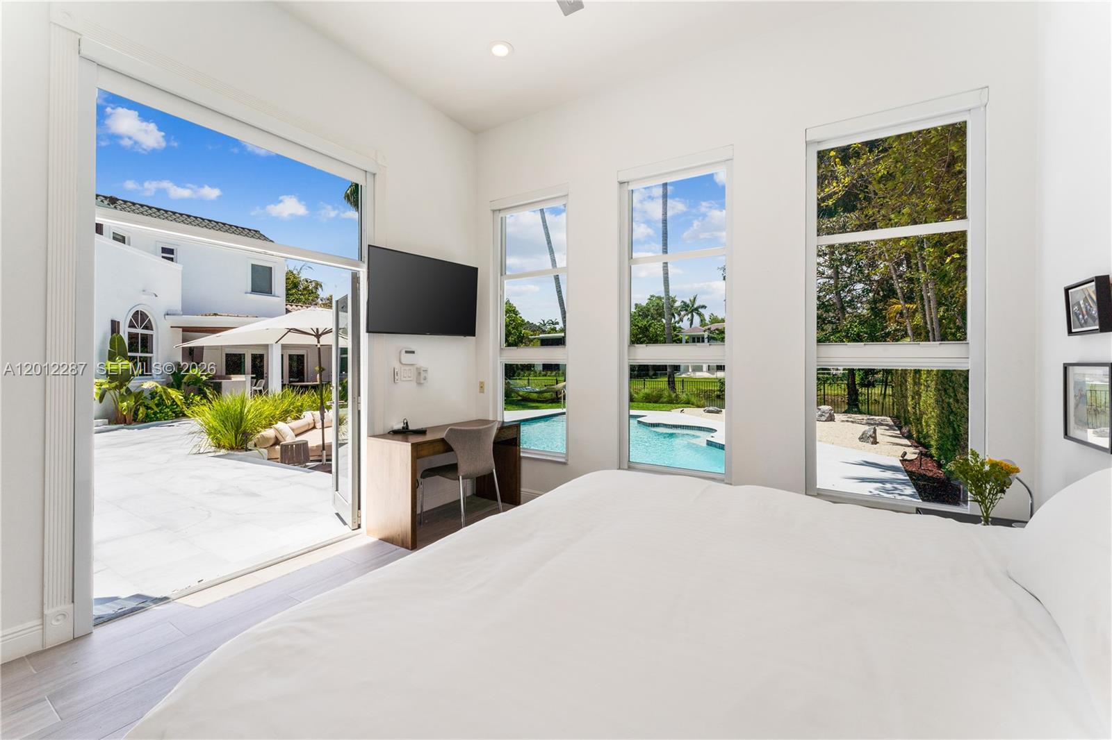 8763 Southwest 61st Place Pinecrest, FL 33156 - Photo 16 of 30 a bedroom with a bed television and a large window
