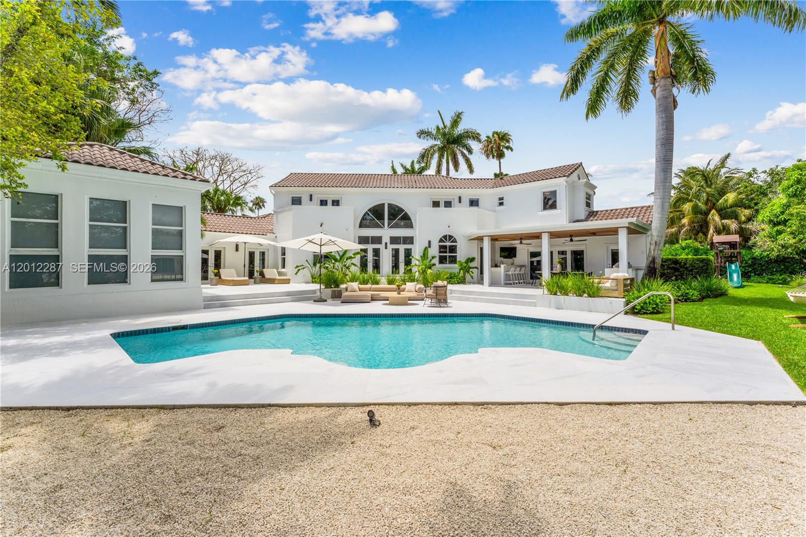 8763 Southwest 61st Place Pinecrest, FL 33156 - Photo 25 of 30 a front view of a house with a yard and potted plants