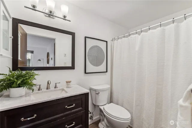 a bathroom with a granite countertop sink vanity mirror and toilet