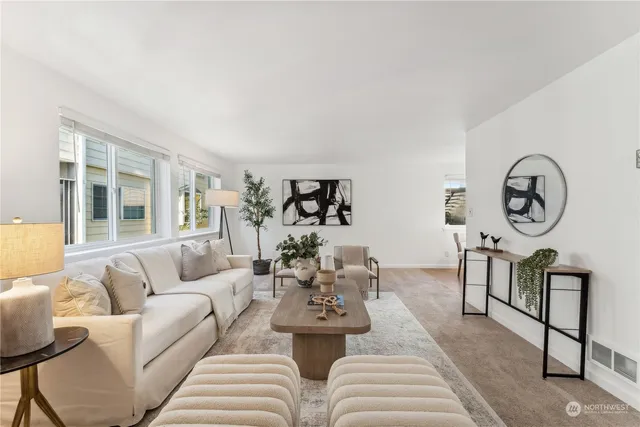 a living room with furniture a rug potted plant and a window