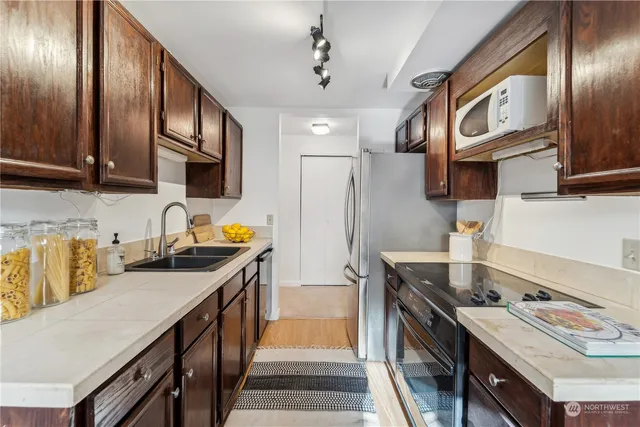 a kitchen with stainless steel appliances granite countertop a stove a sink dishwasher and cabinets with wooden floor