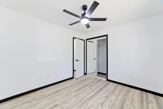 a view of empty room with wooden floor and fan