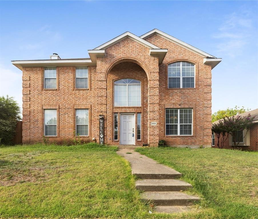 Brick exterior featuring an arched entryway with a two-story window, multiple double-hung windows, and a segmented concrete walkway
