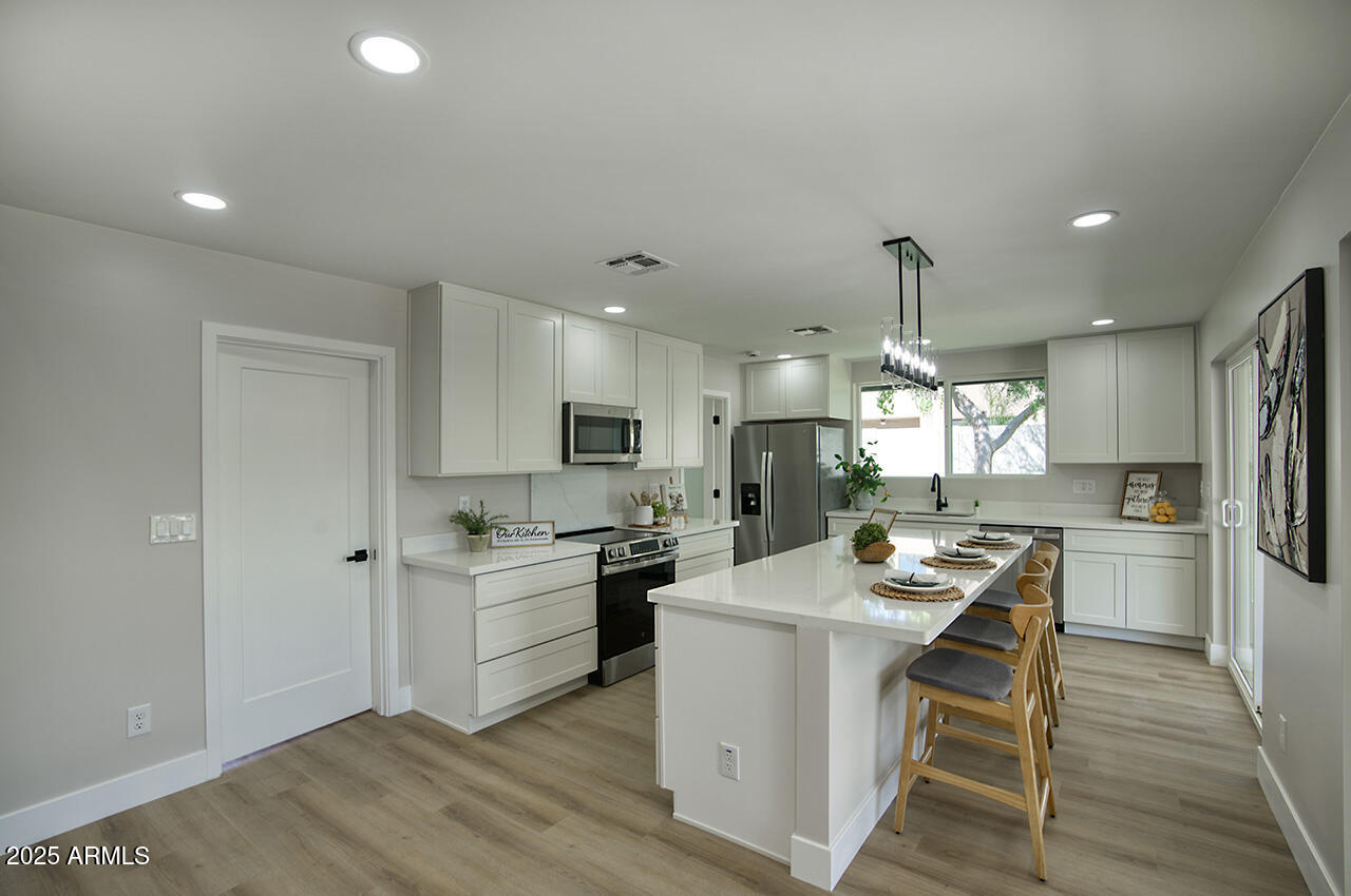 1561 North 26th Street Mesa, AZ 85213 - Photo 12 of 35 a kitchen with a sink a stove a refrigerator and white cabinets