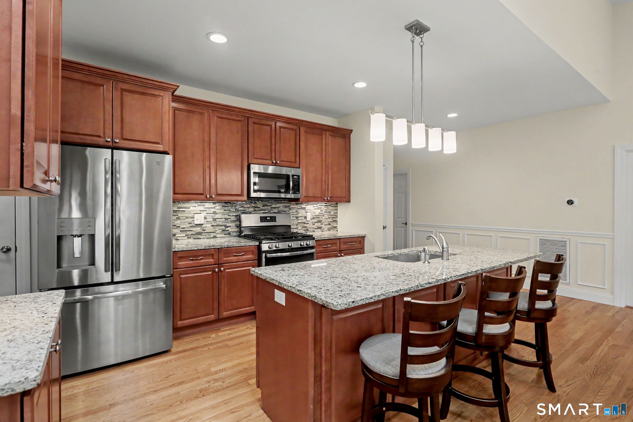223 Meadow Brook Road, Unit 223 Oxford, CT 06478 - Photo 12 of 34 a kitchen with stainless steel appliances granite countertop a kitchen island hardwood floor a dining table and chairs