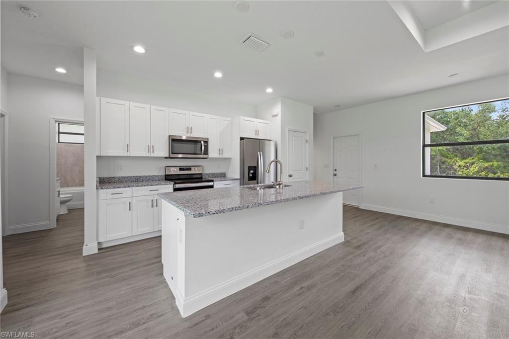 355 Ranier Avenue Lehigh Acres, FL 33974 - Photo 11 of 27 a kitchen with stainless steel appliances granite countertop a stove a sink and a microwave