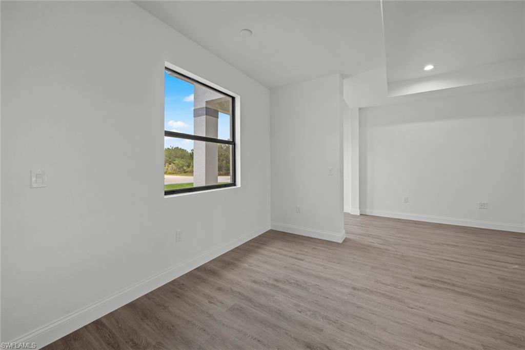 355 Ranier Avenue Lehigh Acres, FL 33974 - Photo 13 of 27 a view of an empty room with wooden floor and a window