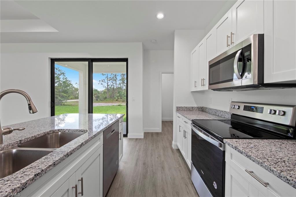 355 Ranier Avenue Lehigh Acres, FL 33974 - Photo 14 of 27 a kitchen with stainless steel appliances granite countertop a sink a stove a microwave and wooden cabinets