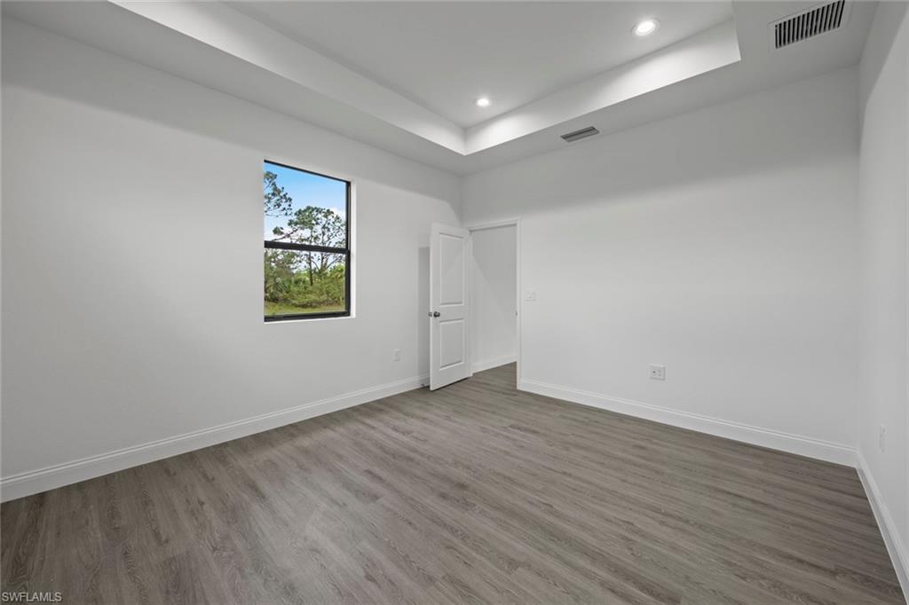 355 Ranier Avenue Lehigh Acres, FL 33974 - Photo 17 of 27 a view of an empty room with wooden floor and a window