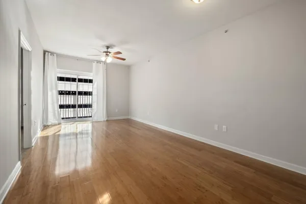 a view of an empty room with a window and wooden floor