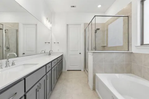 a bathroom with a double vanity sink and mirror with bathtub