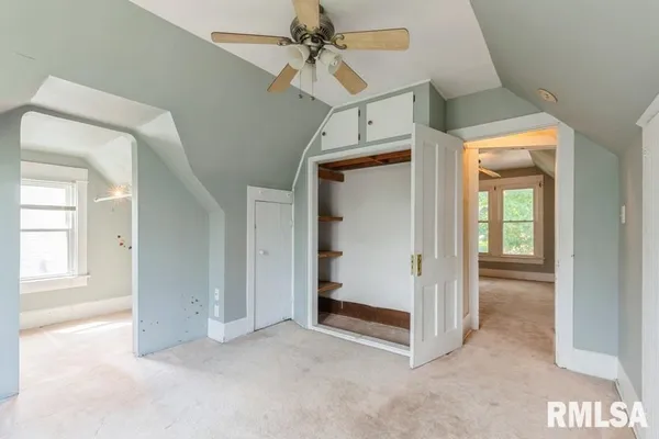 an empty room with windows and fan