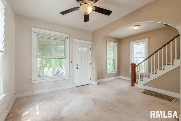 an empty room with ceiling fan and windows