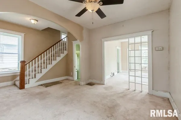 an empty room with windows and fan
