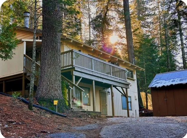 a view of small house with a tree and wooden fence