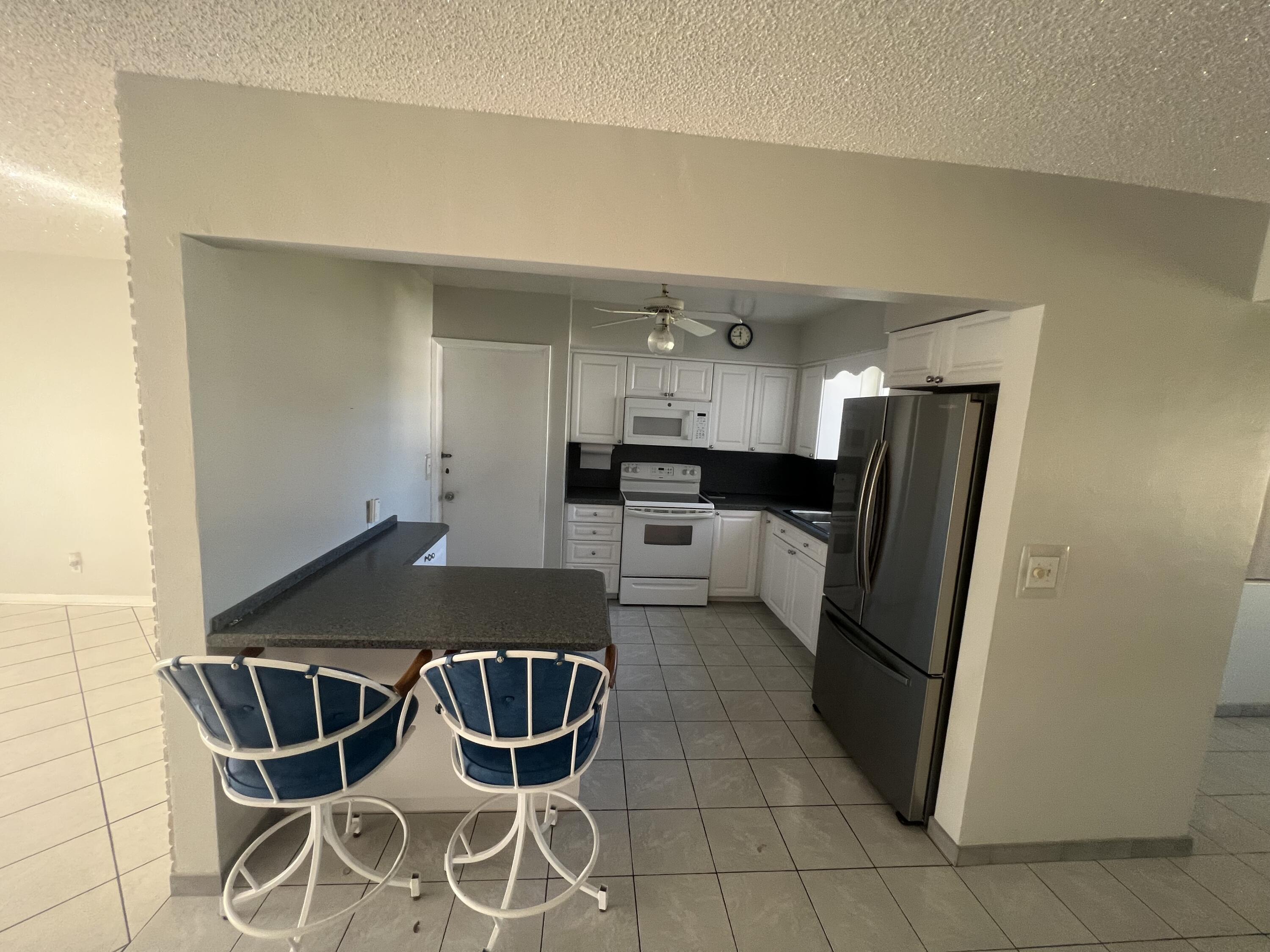 4007 Johnson Street Hollywood, FL 33021 - Photo 6 of 14 a kitchen with stainless steel appliances kitchen island granite countertop a refrigerator a stove a sink dishwasher and white cabinets with wooden floor