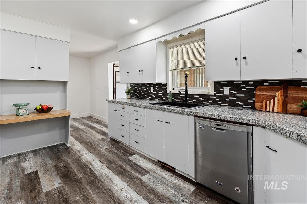 1214 H Street Rupert, ID 83350 - Photo 13 of 35 Kitchen featuring white cabinetry, dishwasher, light countertops, dark wood-style flooring, and backsplash