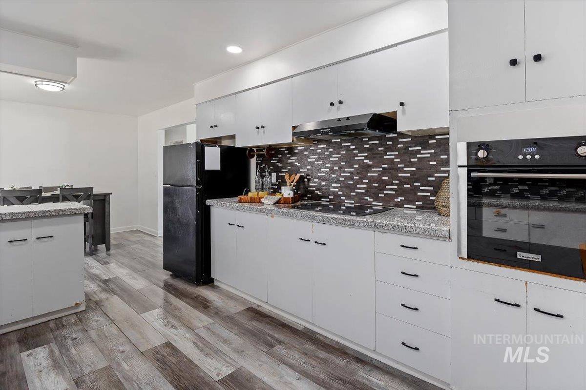 1214 H Street Rupert, ID 83350 - Photo 15 of 35 Kitchen featuring black appliances, white cabinets, light wood finished floors, decorative backsplash, and recessed lighting