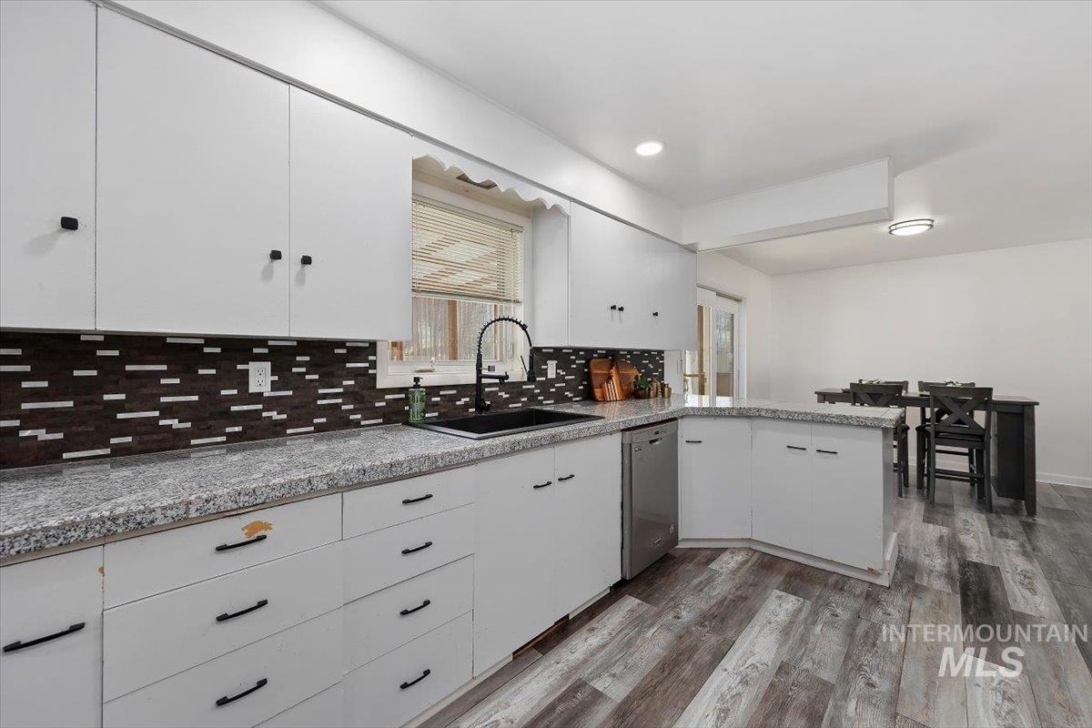 1214 H Street Rupert, ID 83350 - Photo 16 of 35 Kitchen featuring white cabinetry, decorative backsplash, dark wood finished floors, a peninsula, and dishwasher