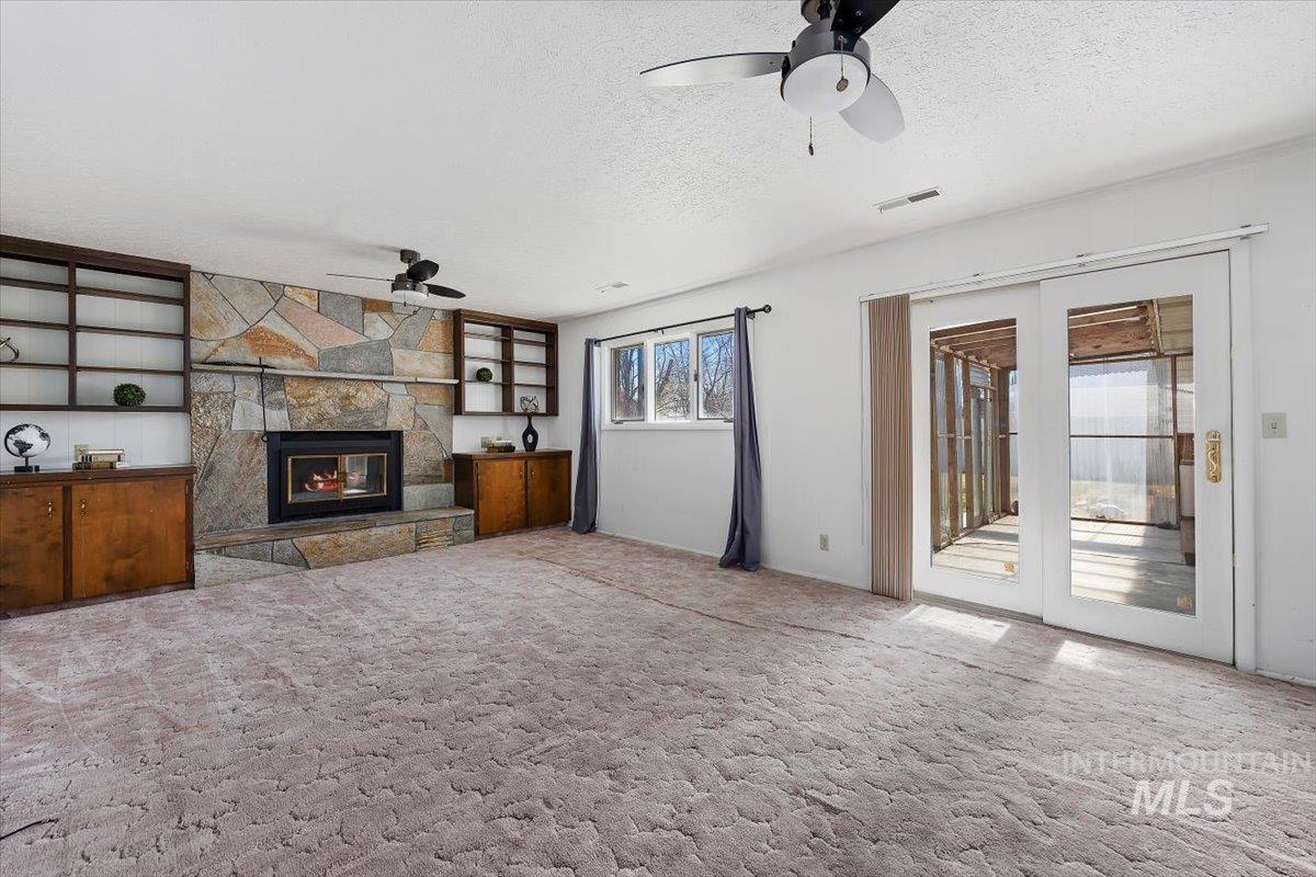 1214 H Street Rupert, ID 83350 - Photo 18 of 35 Unfurnished living room featuring a fireplace, carpet, a ceiling fan, and a textured ceiling