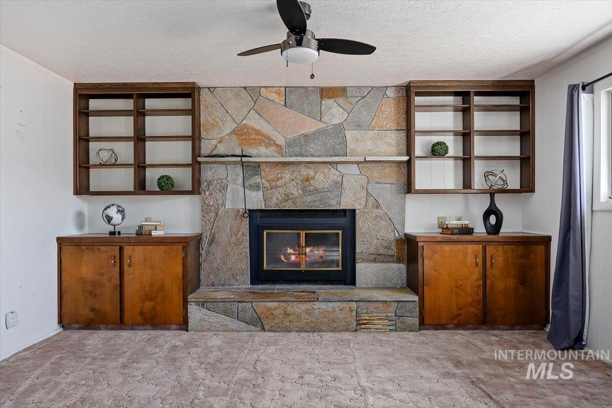 1214 H Street Rupert, ID 83350 - Photo 19 of 35 Carpeted living room featuring a fireplace, ceiling fan, and a textured ceiling