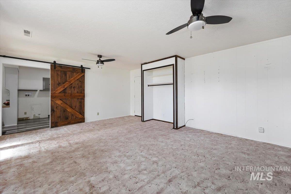 1214 H Street Rupert, ID 83350 - Photo 20 of 35 Unfurnished bedroom with a barn door, ceiling fan, carpet floors, a closet, and electric panel