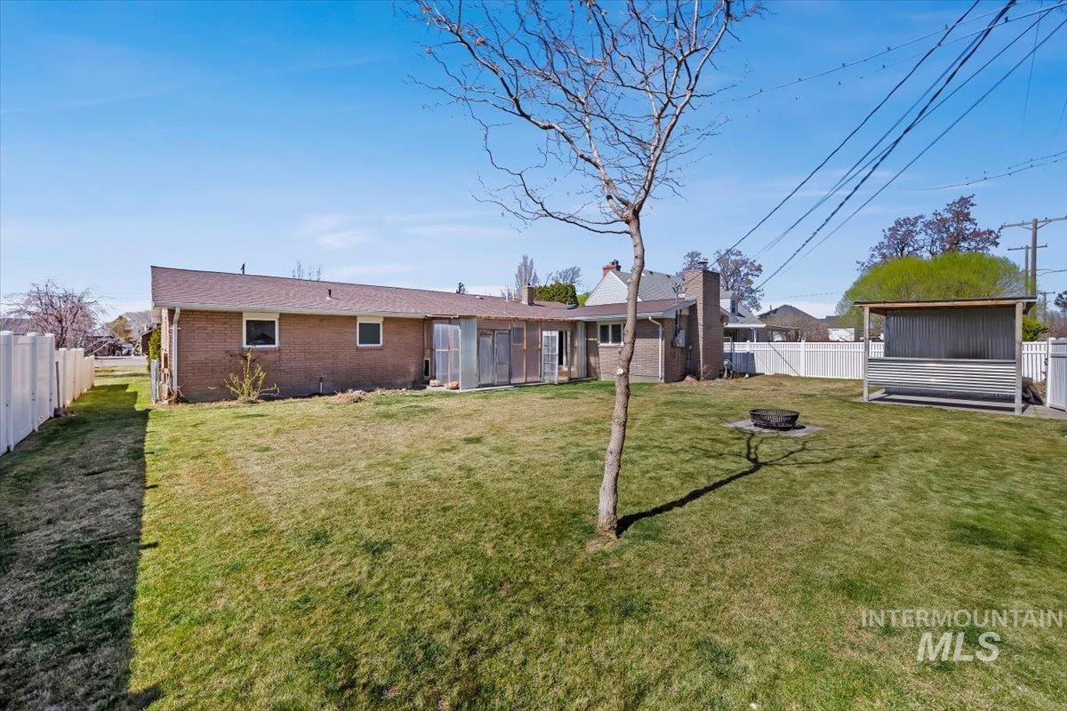 1214 H Street Rupert, ID 83350 - Photo 30 of 35 Rear view of property with a fenced backyard, brick siding, and an outdoor fire pit