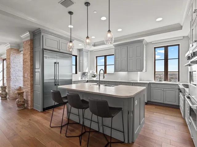 a kitchen with stainless steel appliances granite countertop a sink a stove a refrigerator and island with wooden floor