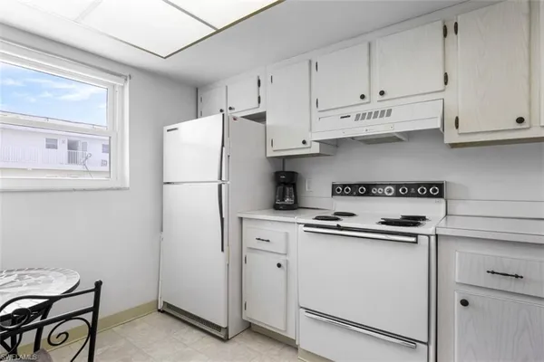a kitchen with white cabinets and white appliances