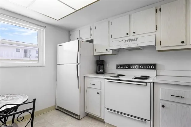 a kitchen with white cabinets and white appliances