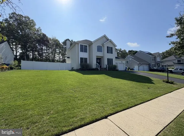 a view of a white house in front of a big yard with large trees