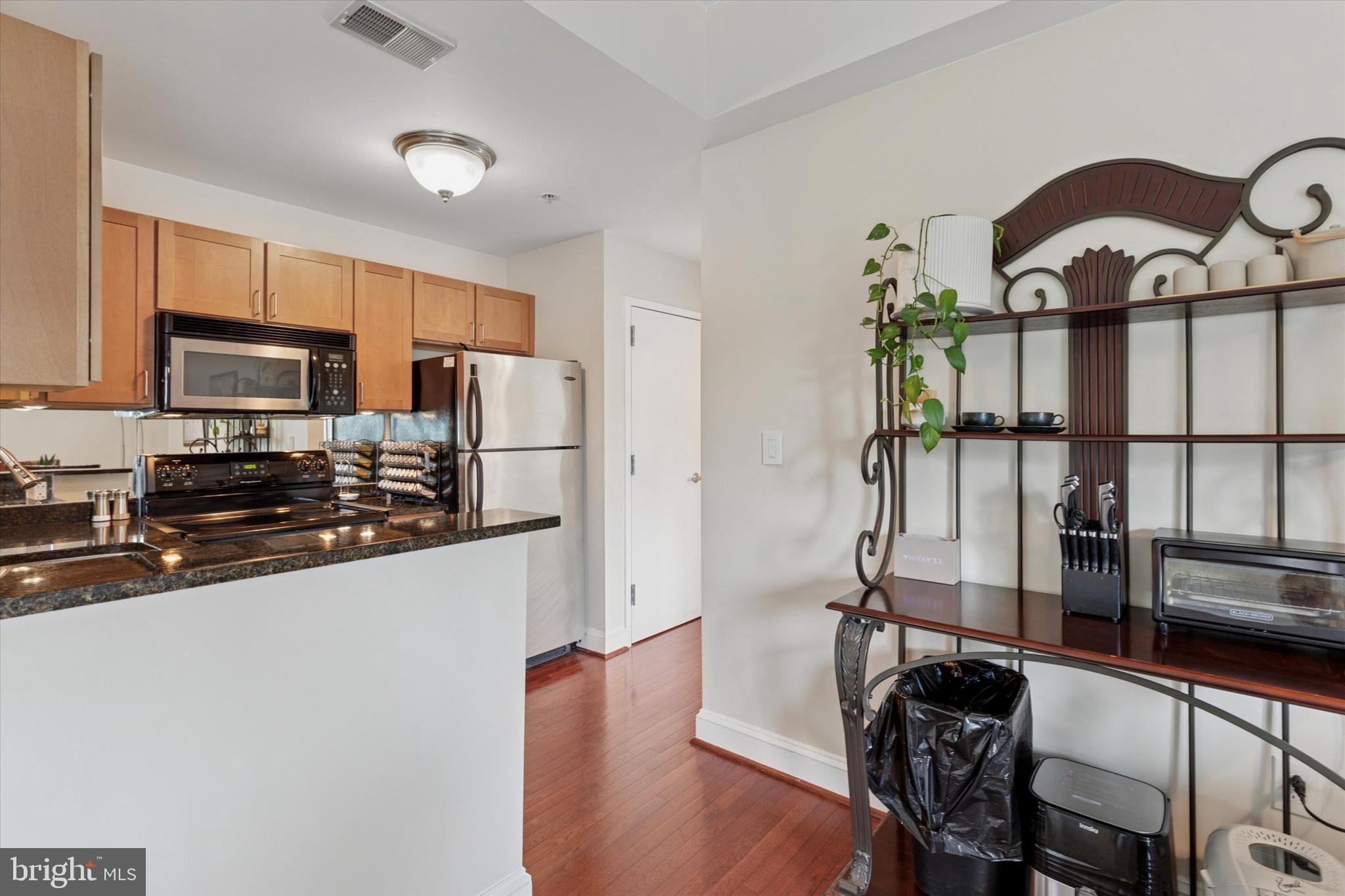 3750 Main Street, Unit 709 Philadelphia, PA 19127 - Photo 2 of 15 a kitchen with stainless steel appliances a refrigerator a stove a sink a dining table and chairs with wooden floor