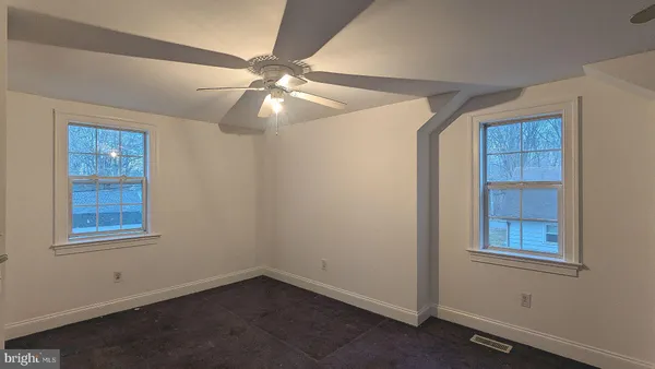 an empty room with closet and a ceiling fan