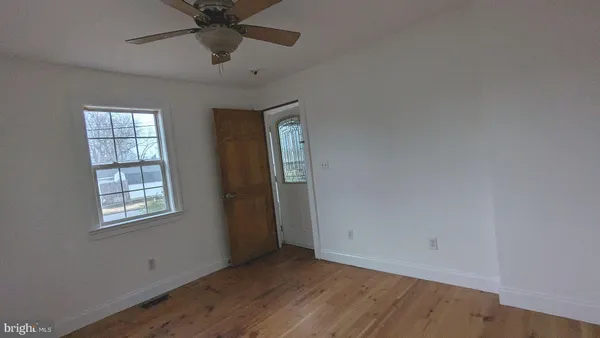a view of an empty room with a window and a chandelier fan