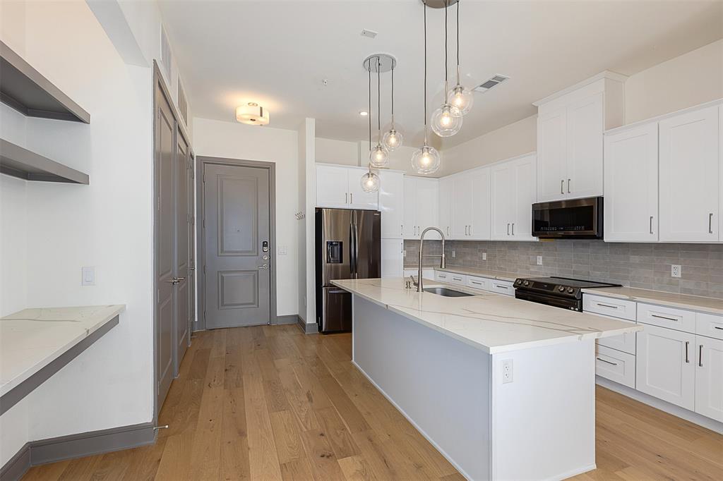 2700 Old Denton Road, Unit 1044 Carrollton, TX 75007 - Photo 2 of 33 Modern kitchen with a large central island featuring a white countertop and undermount sink