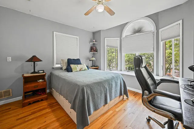 a bedroom with a bed a large window with table and chair