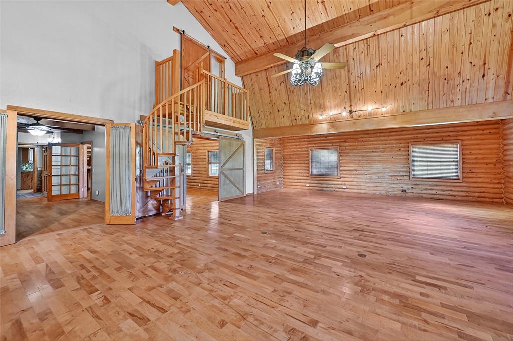 570 Ayres Road Bells, TX 75414 - Photo 13 of 39 Unfurnished living room featuring high vaulted ceiling, a ceiling fan, stairs, rustic walls, and a wood ceiling with exposed beams