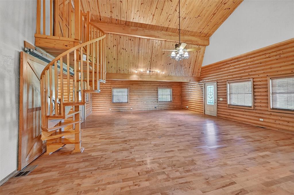 570 Ayres Road Bells, TX 75414 - Photo 14 of 39 Unfurnished living room featuring high vaulted ceiling, log walls, stairs, ceiling fan, and a wooden ceiling with exposed beams