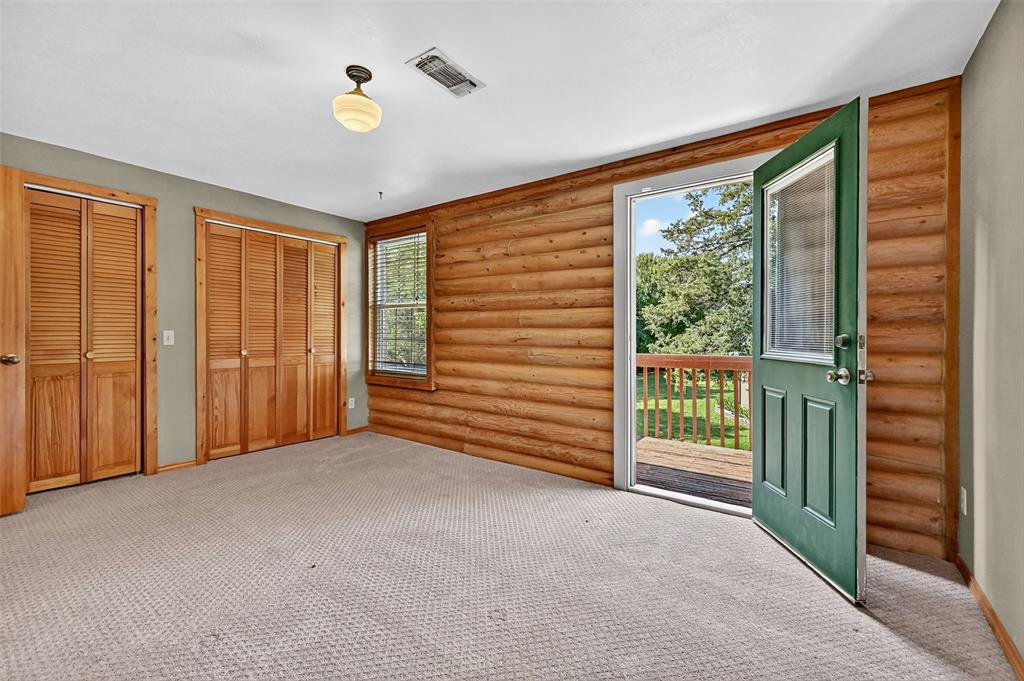 570 Ayres Road Bells, TX 75414 - Photo 22 of 39 Unfurnished bedroom featuring multiple windows, access to outside, two closets, log walls, and light colored carpet