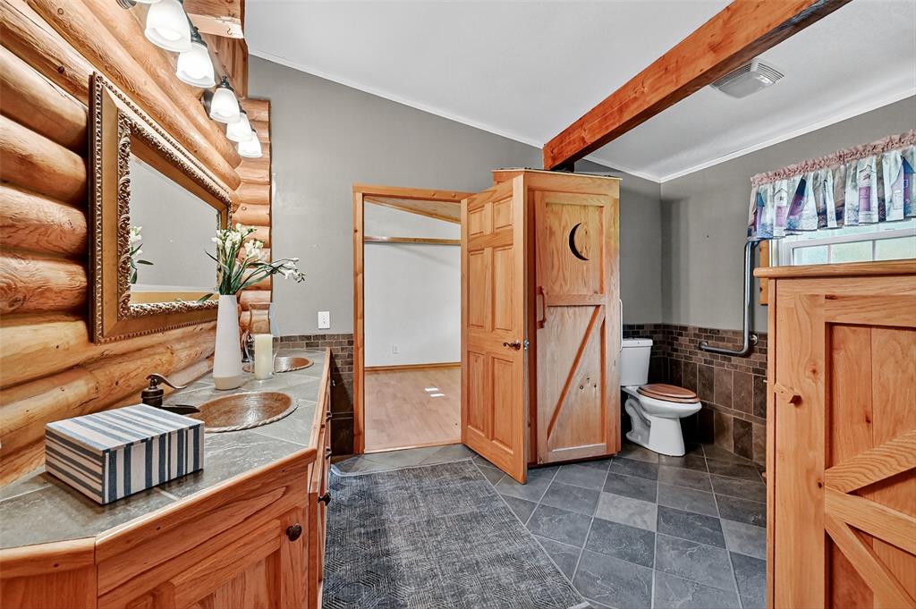 570 Ayres Road Bells, TX 75414 - Photo 24 of 39 Bathroom featuring tile walls, wainscoting, double vanity, and rustic walls