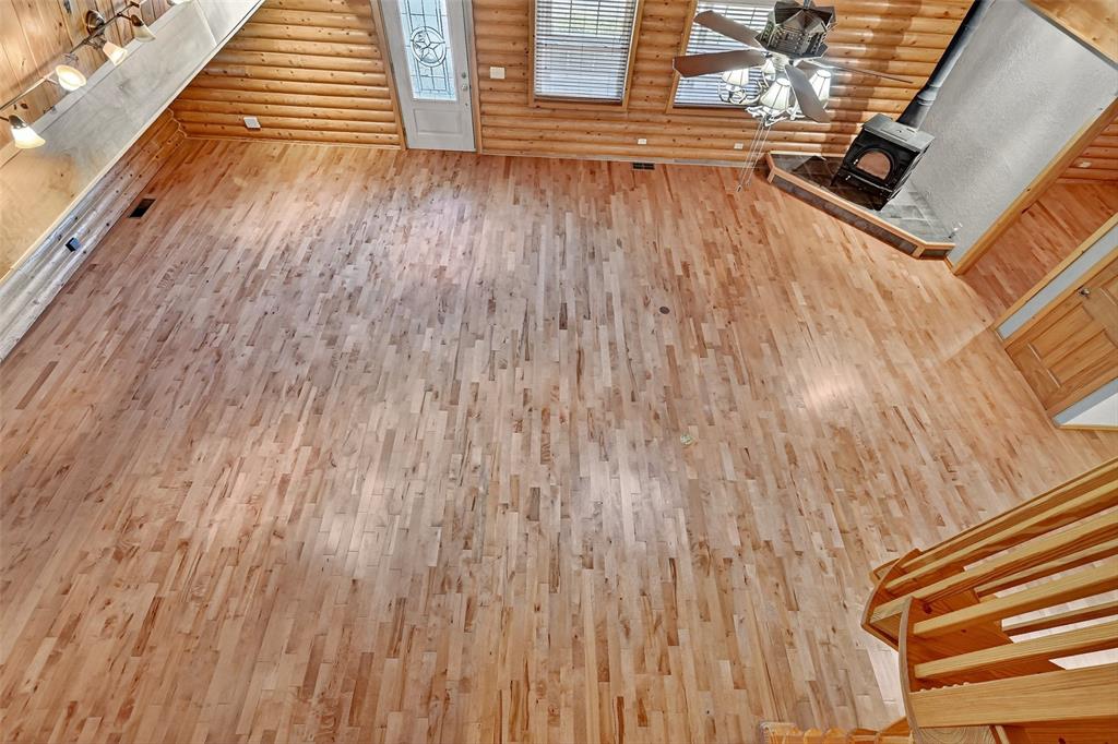 570 Ayres Road Bells, TX 75414 - Photo 27 of 39 Unfurnished living room featuring a wood stove, hardwood / wood-style floors, and rustic walls