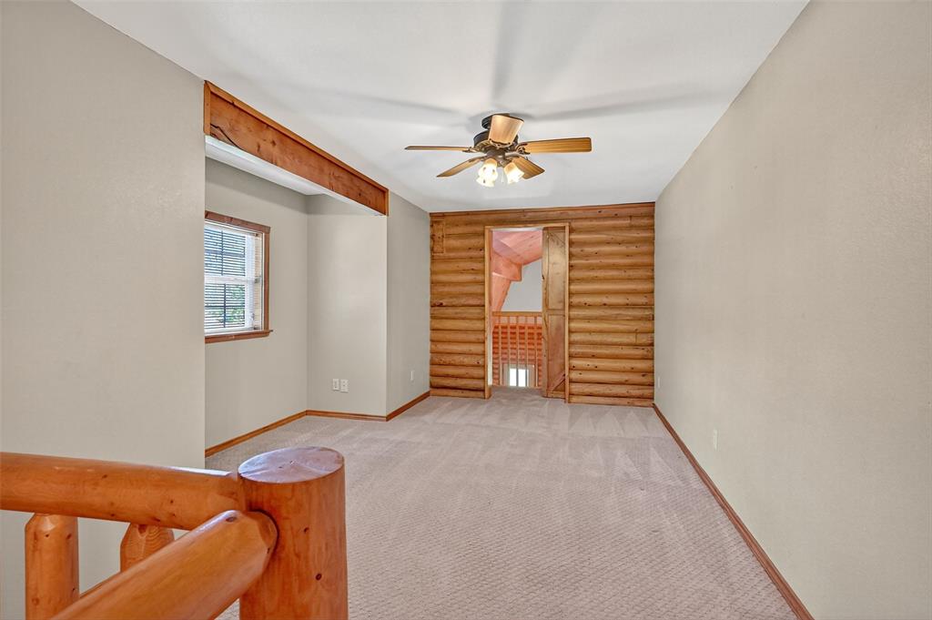 570 Ayres Road Bells, TX 75414 - Photo 28 of 39 Spare room featuring log walls, a ceiling fan, and light carpet