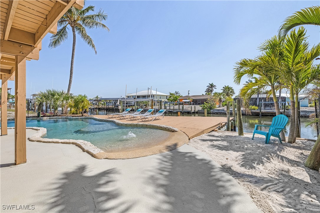 3128 Stringfellow Road St. James City, FL 33956 - Photo 42 of 50 a view of a swimming pool with a lawn chairs under an umbrella