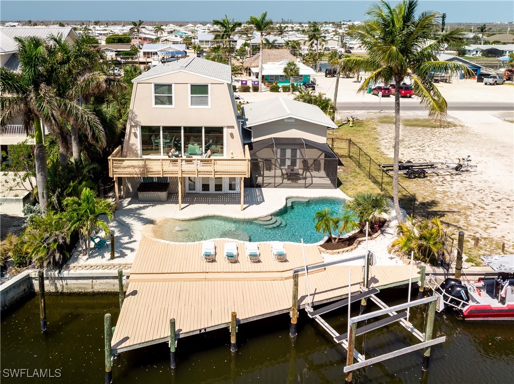 3128 Stringfellow Road St. James City, FL 33956 - Photo 5 of 50 a view of a white house with swimming pool lawn chairs and a barbeque