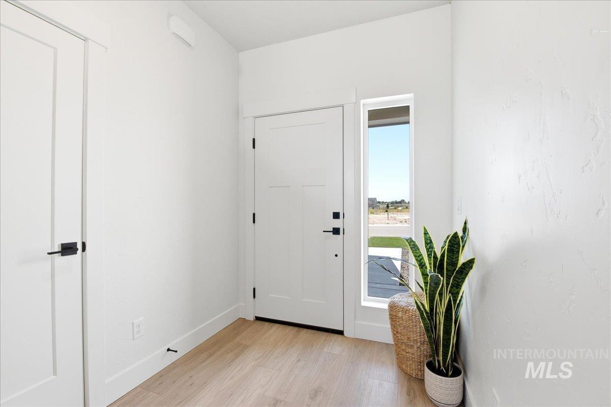 3405 Elliptical Lane Caldwell, ID 83607 - Photo 2 of 17 Entryway featuring a white paneled door with matte black hardware, light wood-finish flooring, and a tall vertical window offering natural illumination