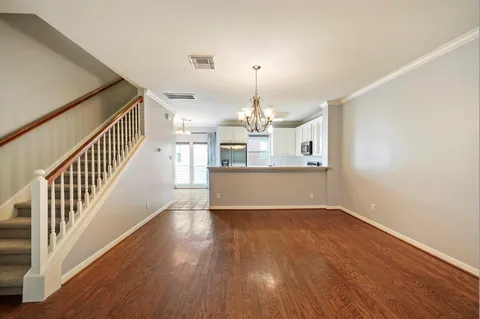 a view of a room with wooden floor staircase and a kitchen